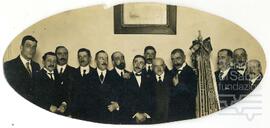 Fotografía de Jesús Guridi rodeado de un grupo de hombres en un acto de la Sociedad Coral de Bilbao.